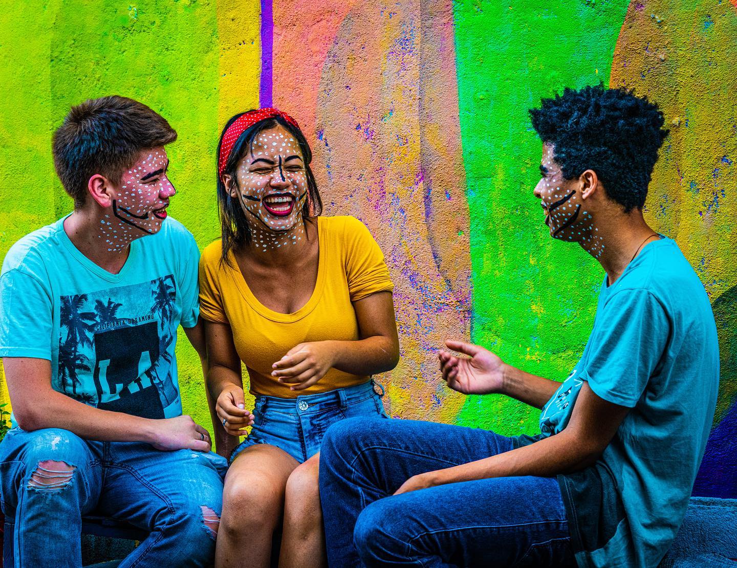 Three people sharing a lively conversation against a brightly colored wall