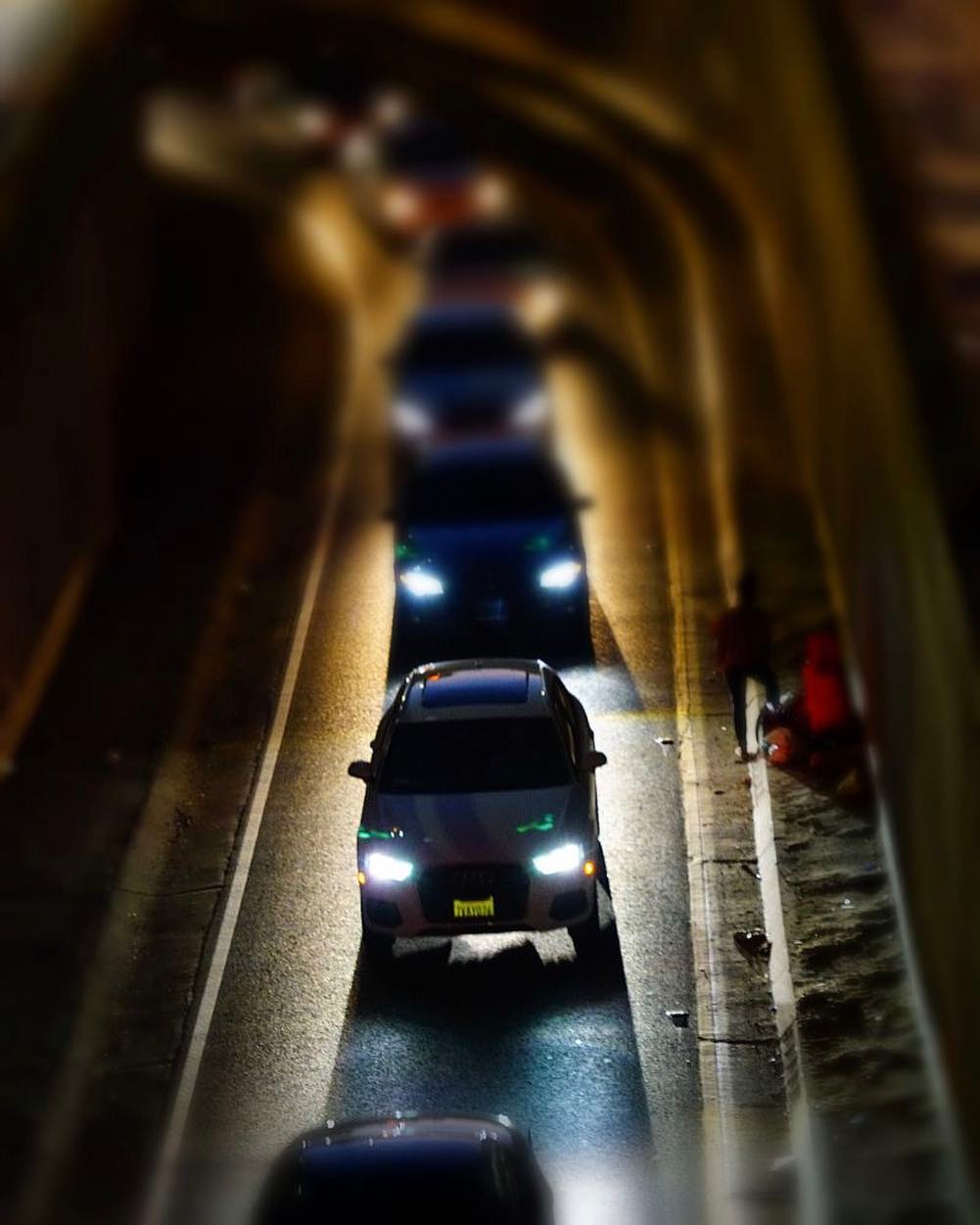 Cars moving through a tunnel illuminated by repeating lights