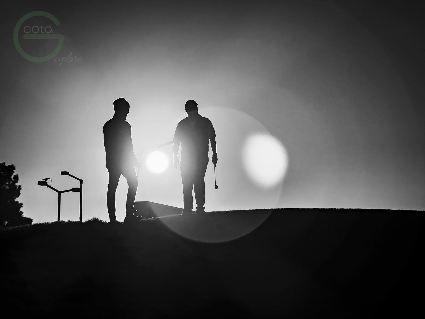 Two silhouetted figures walking across a ridge against the sun