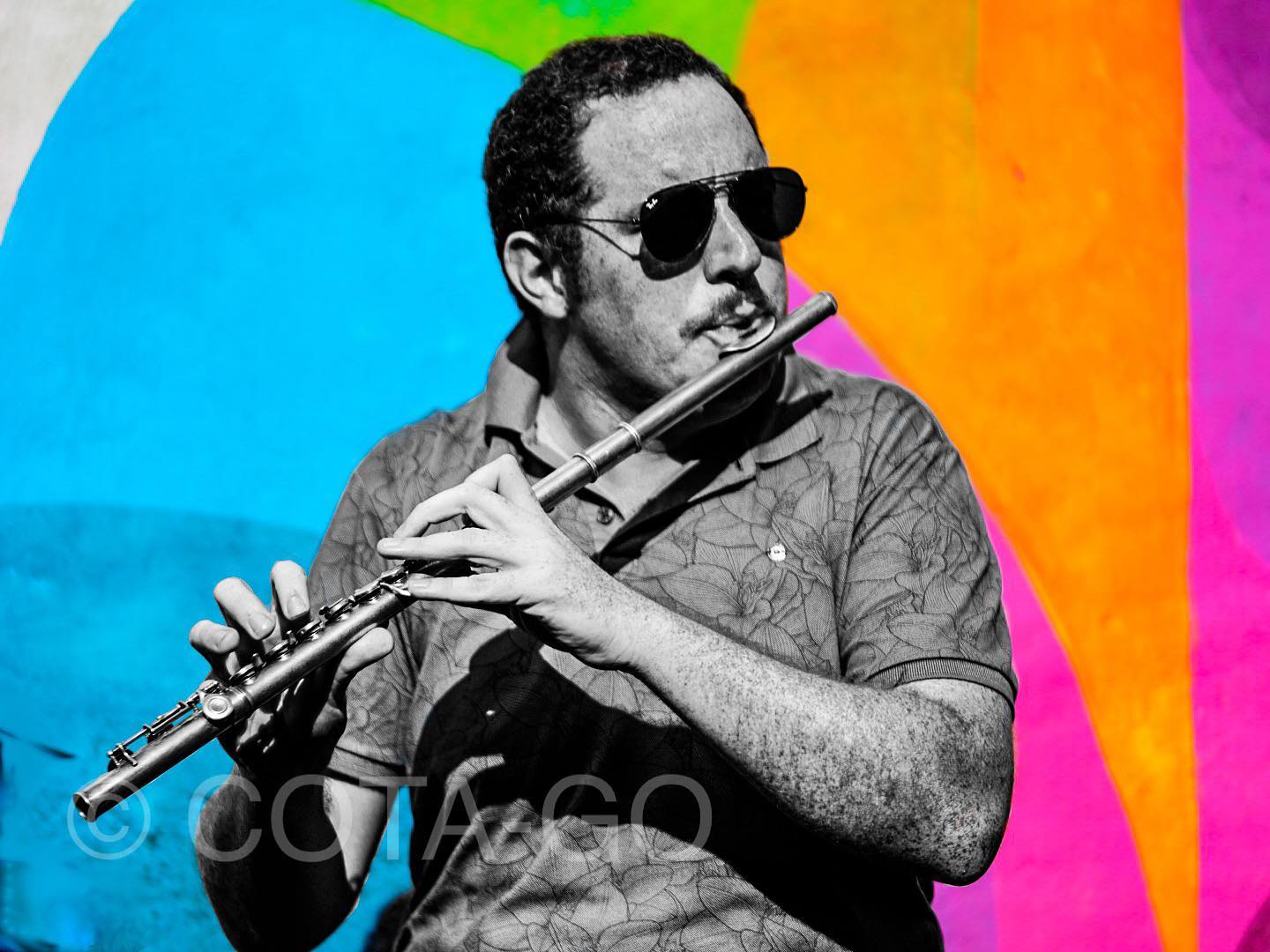 A flutist pictured against a vivid geometric field of color